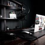 Creative workspace featuring a laptop, microphone, and clapperboard on a wooden desk, ideal for podcasting.