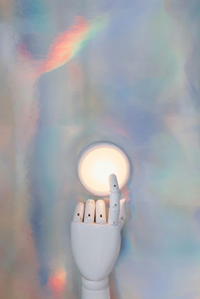 pexels-photo-8849288-8849288 A robotic hand reaching towards a glowing circle on a pastel abstract background, hinting at advanced technology.